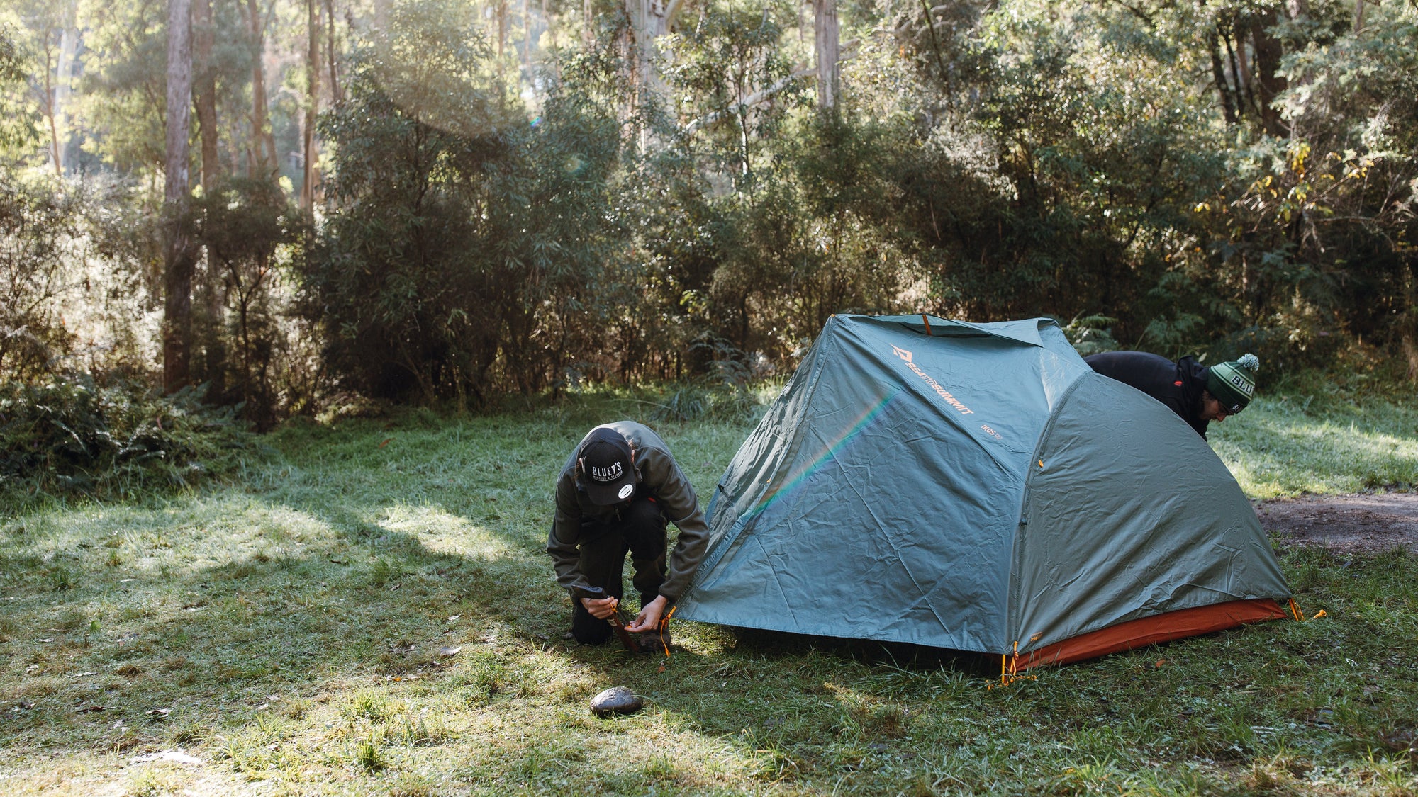 Person setting up a tent in a forest