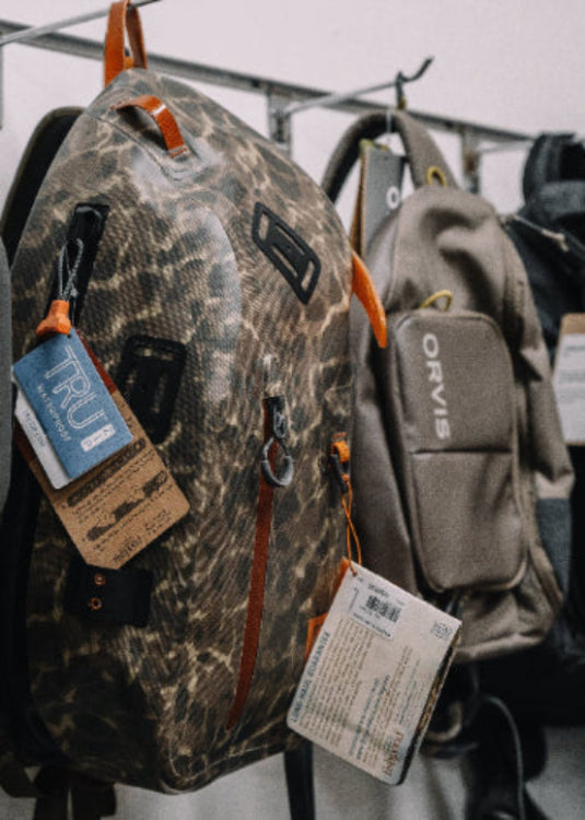Camouflage backpack with tags hanging on a rack