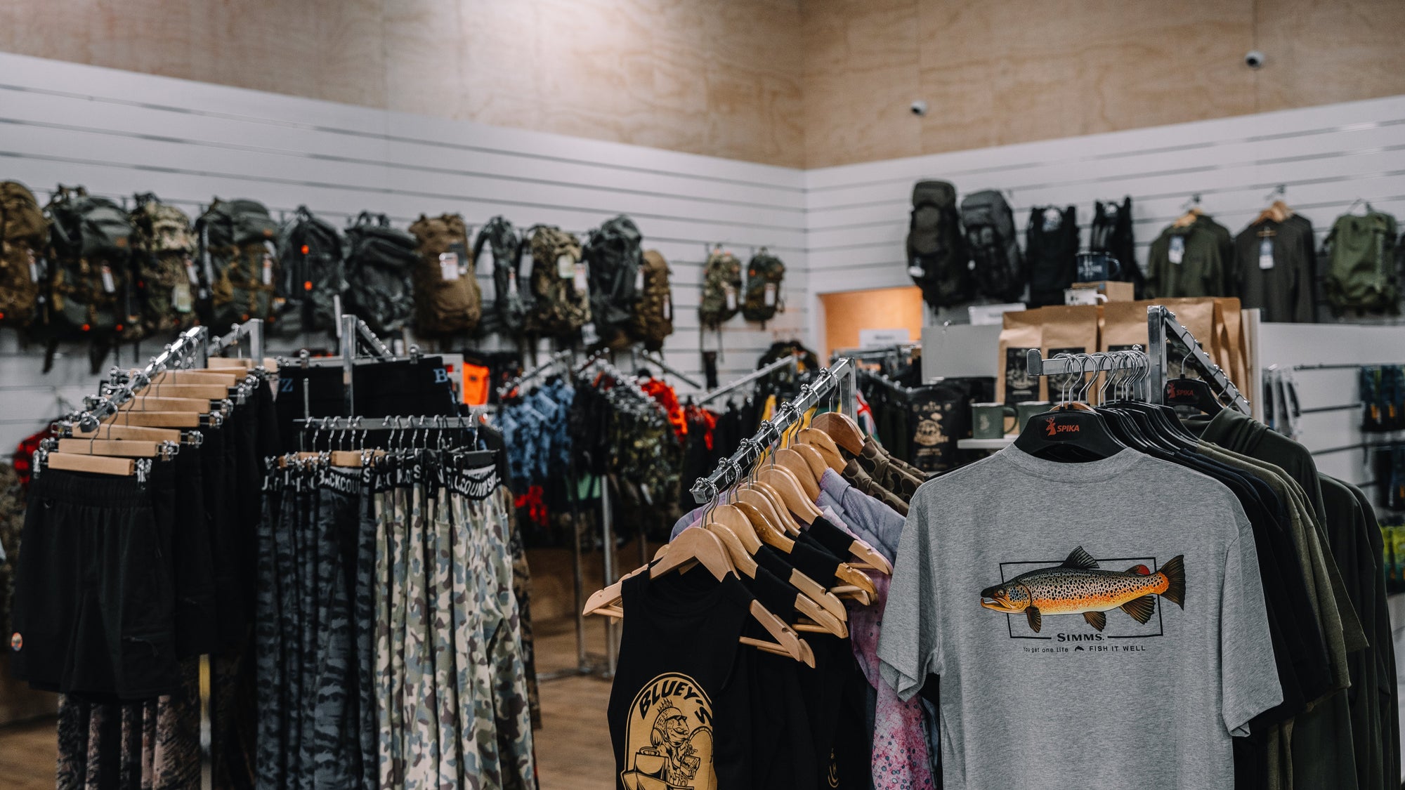 Store interior with clothing racks displaying various garments and a gray t-shirt with a fish graphic.